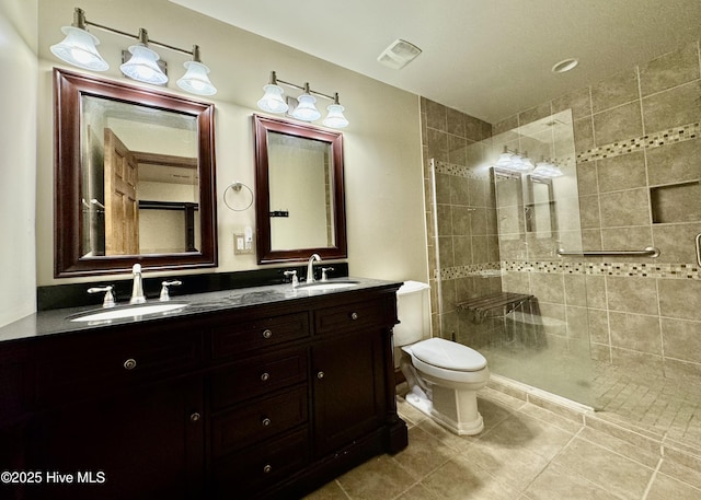 bathroom featuring tile patterned flooring, vanity, tiled shower, and toilet