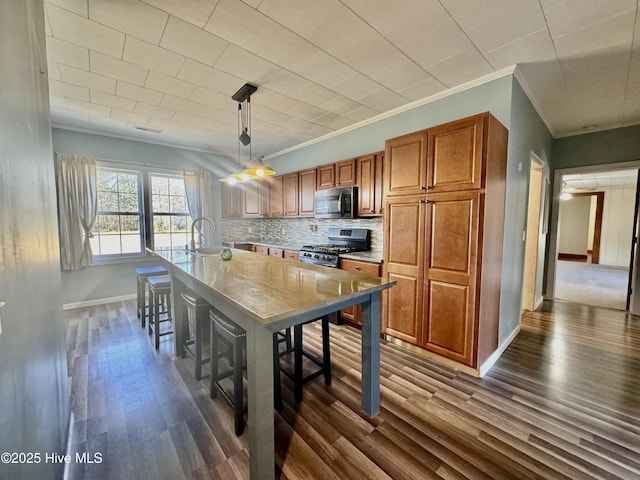 kitchen featuring dark wood-type flooring, sink, hanging light fixtures, a kitchen breakfast bar, and stainless steel appliances