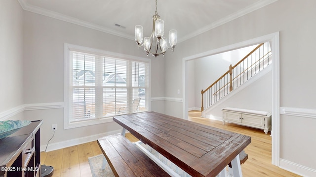 dining space featuring an inviting chandelier, crown molding, and light hardwood / wood-style flooring