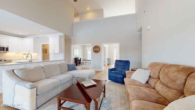 living room with light hardwood / wood-style floors, sink, and a high ceiling