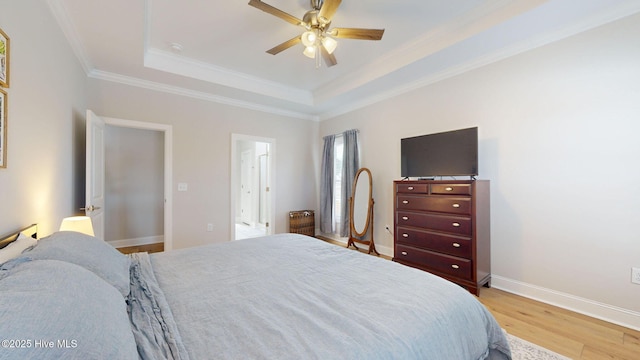 bedroom featuring ornamental molding, ceiling fan, light wood-type flooring, and a tray ceiling