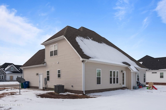 snow covered house featuring central air condition unit