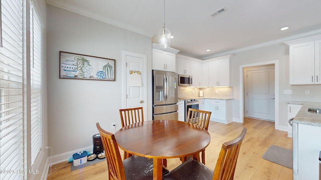 dining room with crown molding and light hardwood / wood-style flooring