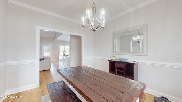 dining area with crown molding, a notable chandelier, and light hardwood / wood-style flooring