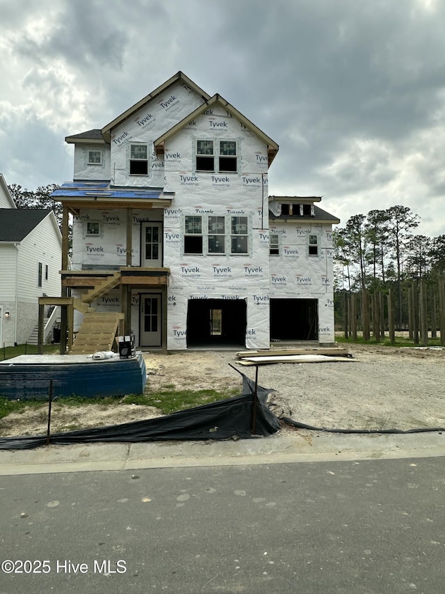 unfinished property featuring stairs, a garage, and stone siding