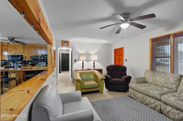 living room with beamed ceiling, ceiling fan, and a textured ceiling