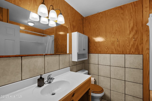 bathroom featuring tile walls, a shower with shower curtain, vanity, toilet, and a chandelier