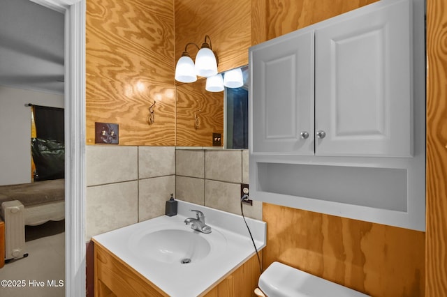 bathroom featuring tasteful backsplash, vanity, toilet, and tile walls