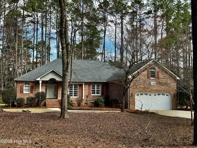 view of front facade featuring brick siding, roof with shingles, an attached garage, crawl space, and driveway