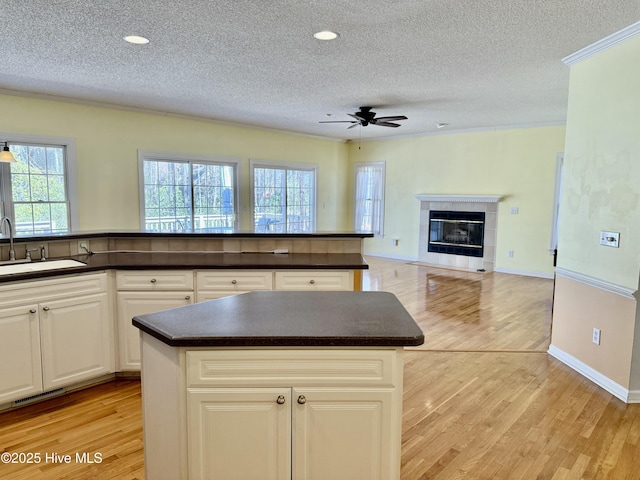 kitchen featuring dark countertops, visible vents, a sink, and light wood-style flooring