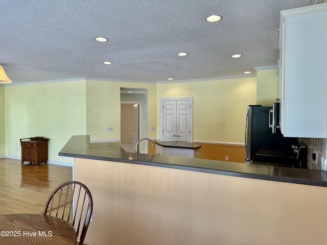 kitchen with a textured ceiling, dark countertops, wood finished floors, and recessed lighting