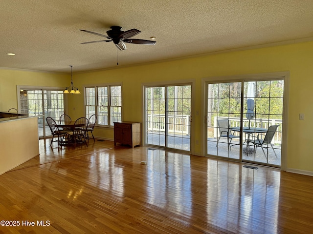 living area featuring a ceiling fan, visible vents, a textured ceiling, and wood finished floors