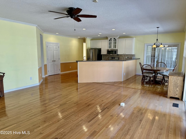 kitchen with white cabinetry, appliances with stainless steel finishes, light wood-type flooring, dark countertops, and glass insert cabinets