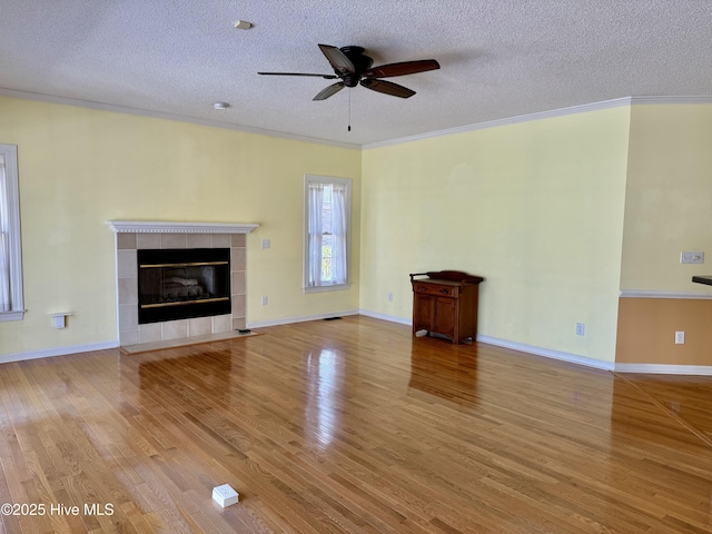 unfurnished living room featuring ornamental molding, a fireplace, a textured ceiling, and wood finished floors