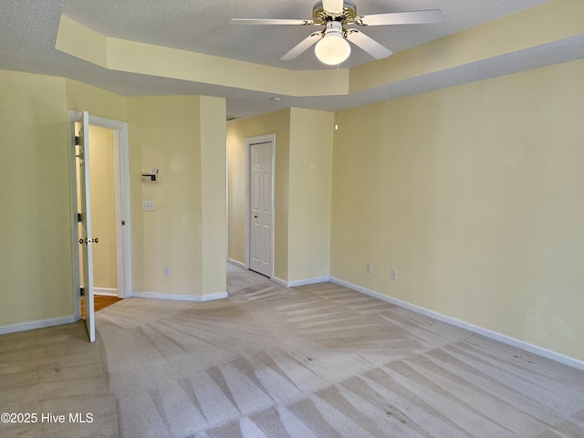 unfurnished room featuring a textured ceiling, ceiling fan, light colored carpet, and baseboards