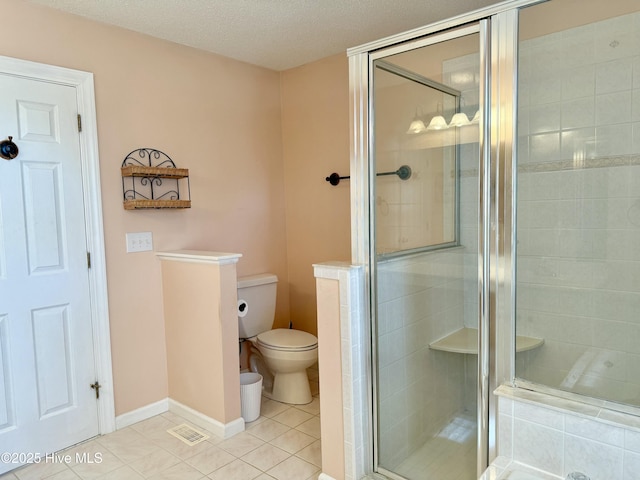 bathroom featuring a stall shower, baseboards, toilet, tile patterned floors, and a textured ceiling