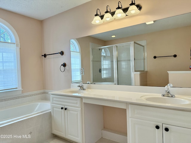 bathroom with a stall shower, a garden tub, a sink, and double vanity