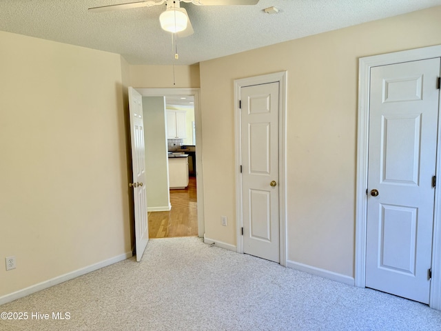 unfurnished bedroom with carpet floors, a ceiling fan, baseboards, and a textured ceiling