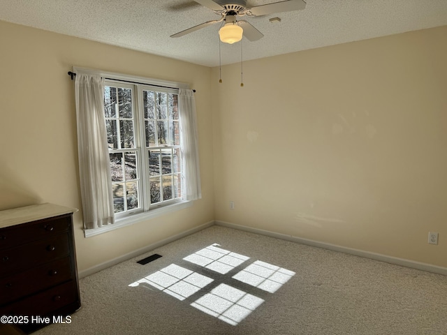 unfurnished room featuring a textured ceiling, carpet flooring, visible vents, and baseboards