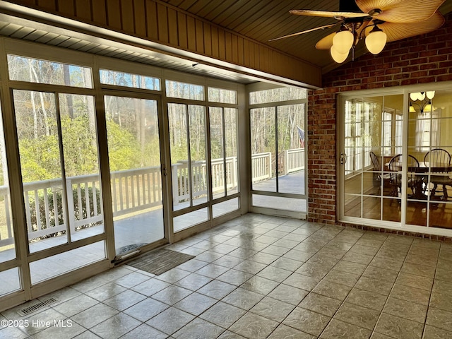 unfurnished sunroom with vaulted ceiling, ceiling fan, and visible vents