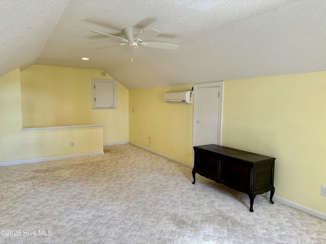 bonus room with a wall unit AC, ceiling fan, a textured ceiling, and light colored carpet