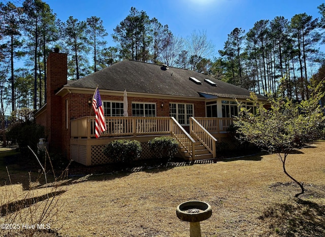 rear view of house with a wooden deck, a chimney, and brick siding