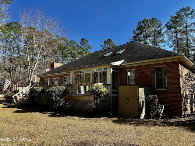 back of house featuring a deck, brick siding, a chimney, and stairway