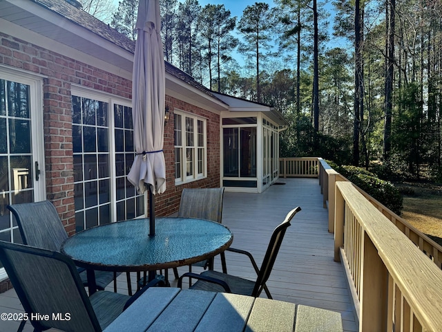 wooden terrace featuring outdoor dining area and a sunroom