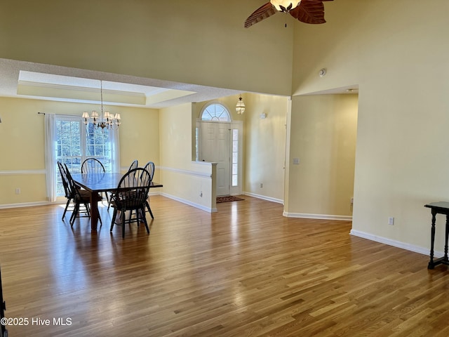 dining space featuring a tray ceiling, wood finished floors, and baseboards