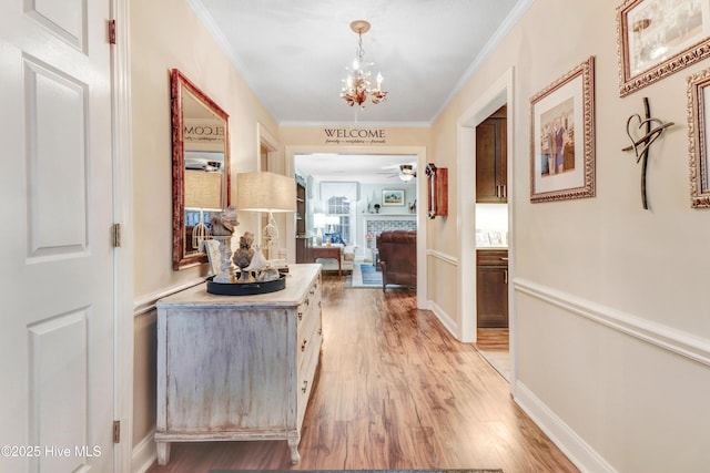 hallway featuring ornamental molding, a chandelier, and light hardwood / wood-style flooring