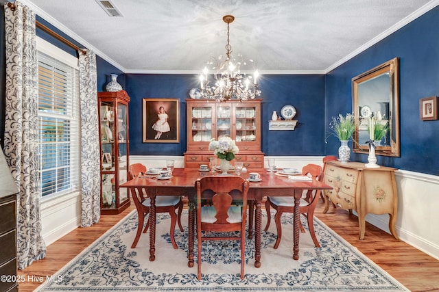 dining room with crown molding, hardwood / wood-style floors, a textured ceiling, and a chandelier