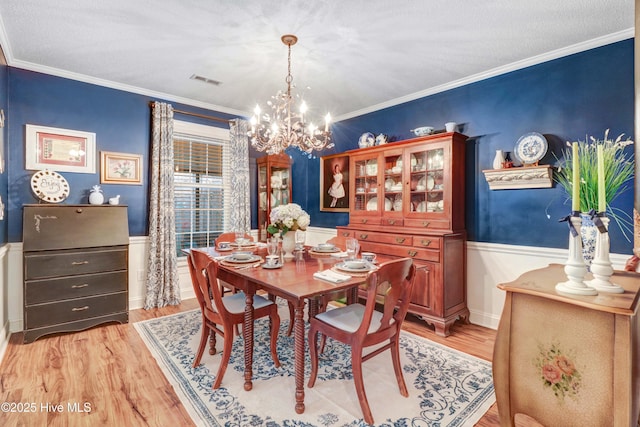 dining space featuring an inviting chandelier, ornamental molding, and light wood-type flooring