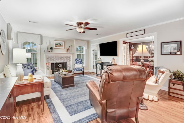 living room with light hardwood / wood-style flooring, crown molding, a fireplace, and ceiling fan