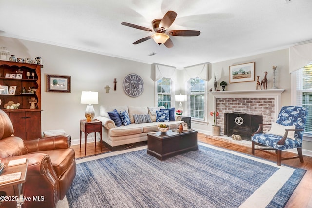 living room featuring hardwood / wood-style flooring, a fireplace, ornamental molding, and ceiling fan