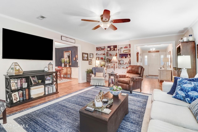 living room with ornamental molding, ceiling fan with notable chandelier, and hardwood / wood-style floors