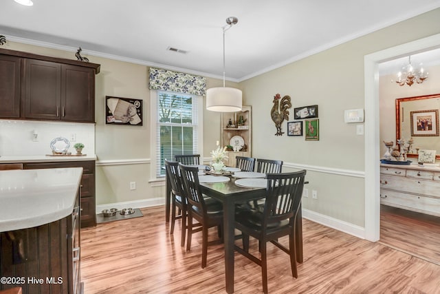 dining area featuring an inviting chandelier, ornamental molding, and light wood-type flooring