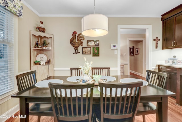 dining space featuring ornamental molding and light wood-type flooring