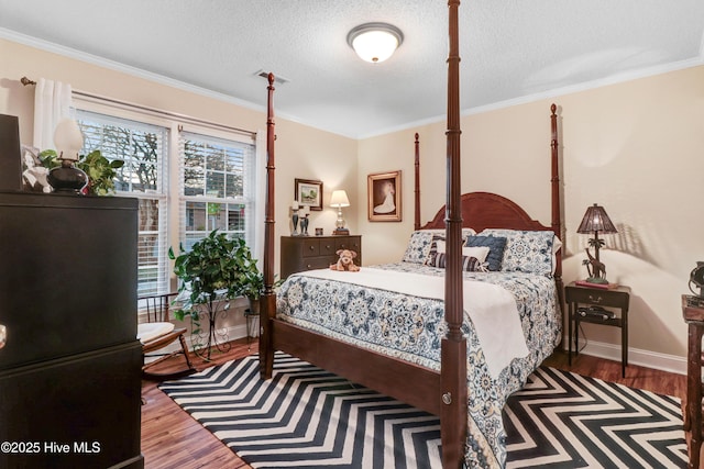 bedroom featuring crown molding, wood-type flooring, and a textured ceiling