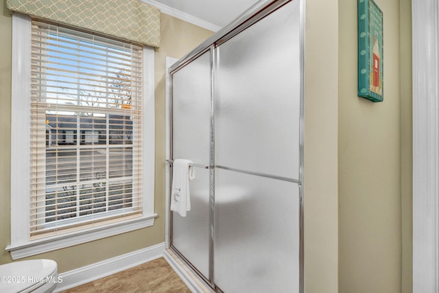 bathroom with a shower with door, ornamental molding, and toilet