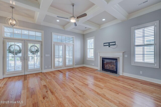 unfurnished living room featuring beamed ceiling, a wealth of natural light, and light hardwood / wood-style floors