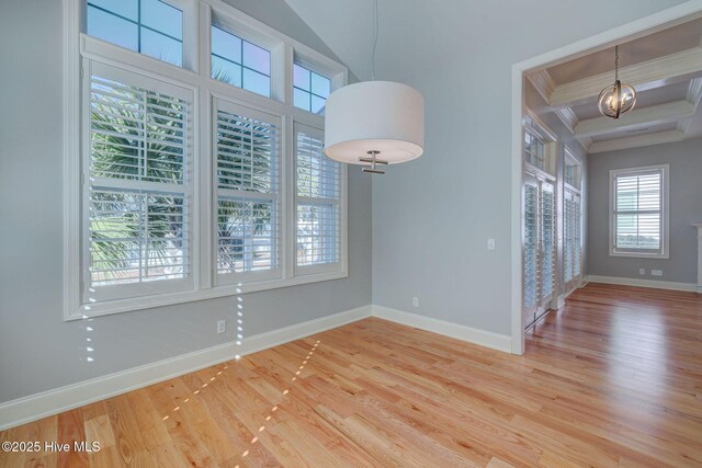 kitchen featuring stainless steel appliances, light stone counters, ornamental molding, a healthy amount of sunlight, and wall chimney exhaust hood