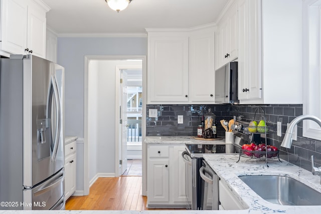 kitchen featuring sink, appliances with stainless steel finishes, white cabinetry, ornamental molding, and decorative backsplash