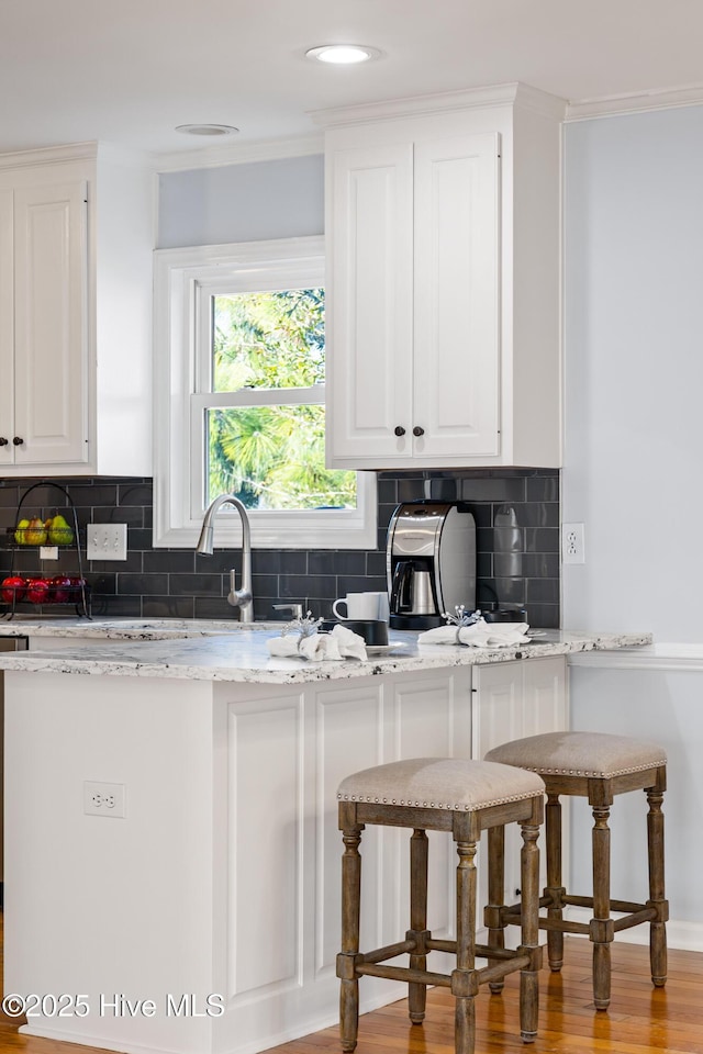 kitchen with decorative backsplash, light stone countertops, and white cabinets