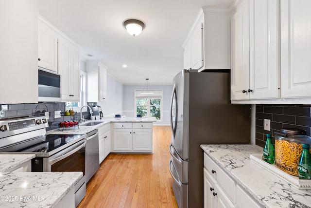 kitchen with sink, light hardwood / wood-style flooring, appliances with stainless steel finishes, pendant lighting, and white cabinets