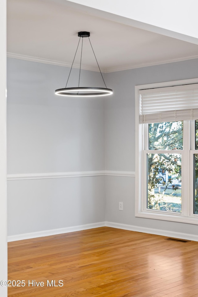 unfurnished dining area featuring ornamental molding and wood-type flooring