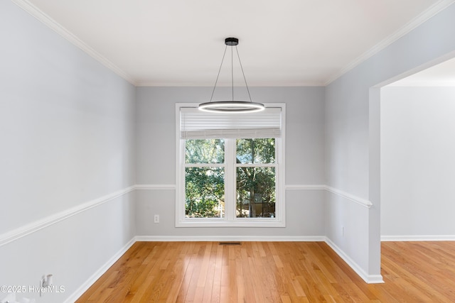 empty room with hardwood / wood-style floors and crown molding