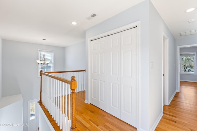 hall with an inviting chandelier and light hardwood / wood-style flooring