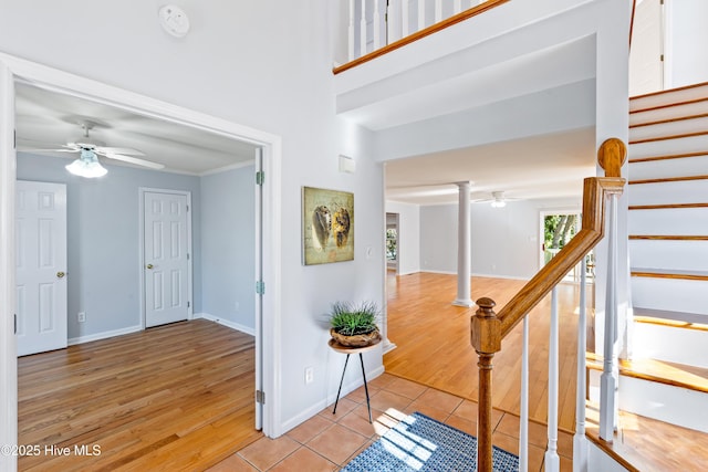 foyer entrance with crown molding, light hardwood / wood-style flooring, ceiling fan, and ornate columns