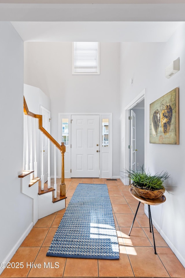 foyer entrance featuring light tile patterned flooring and a towering ceiling