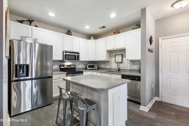 kitchen featuring sink, a breakfast bar area, appliances with stainless steel finishes, a kitchen island, and white cabinets